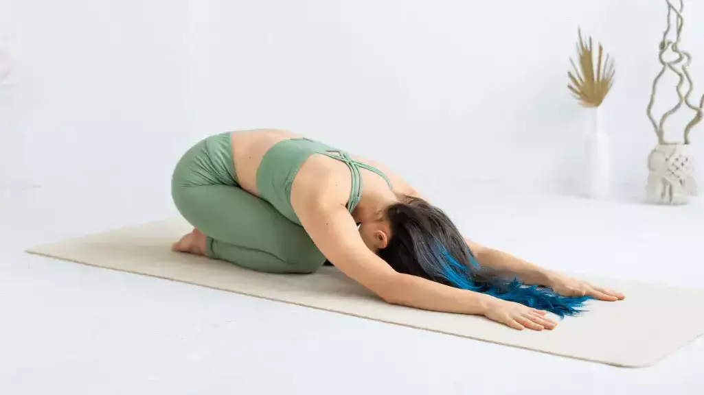 Woman sitting on heels with head lowered to floor in Child's