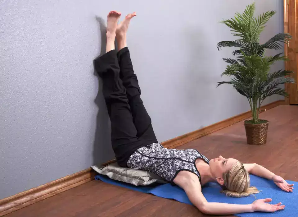"Yoga practitioner in Legs up the Wall Pose with body reclined and legs against wall."