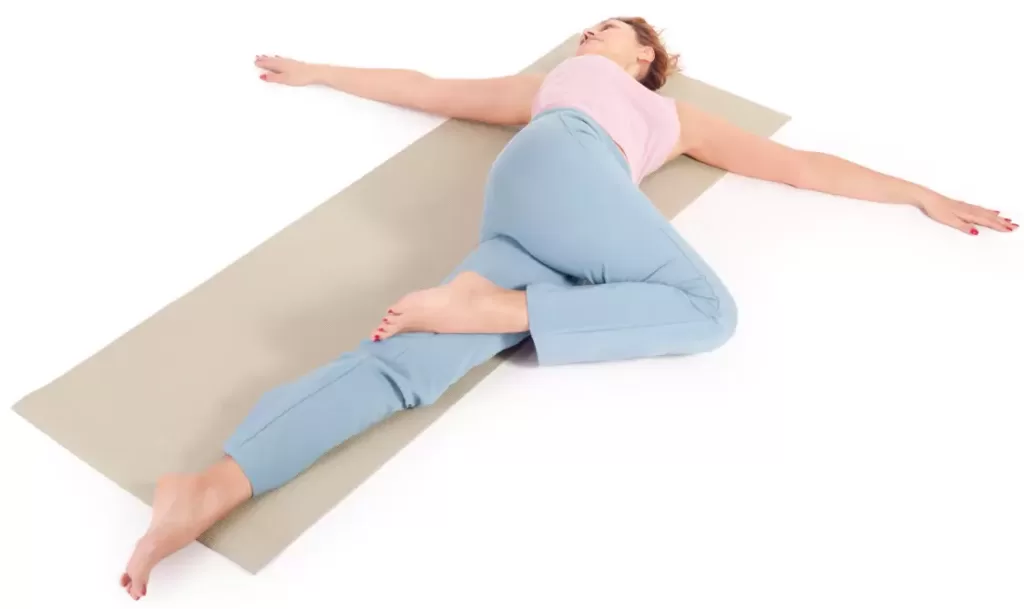 "Yoga practitioner twisting in reclining position with bottom knee bent."