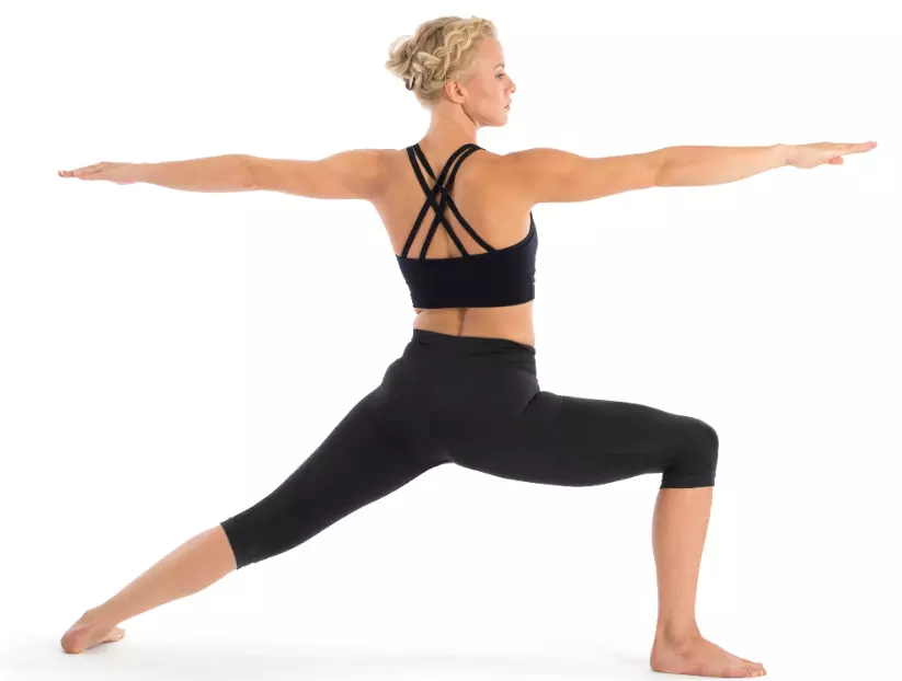  "Yoga practitioner in Warrior II pose with arms reaching sideways."