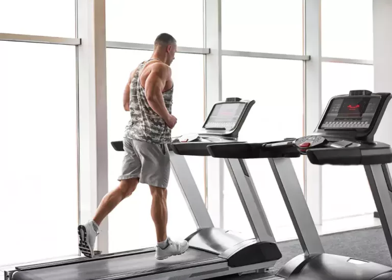 fit man wearing athletic clothing runs on a treadmill, showing off his toned muscles, lean physique and excellent form and posture.