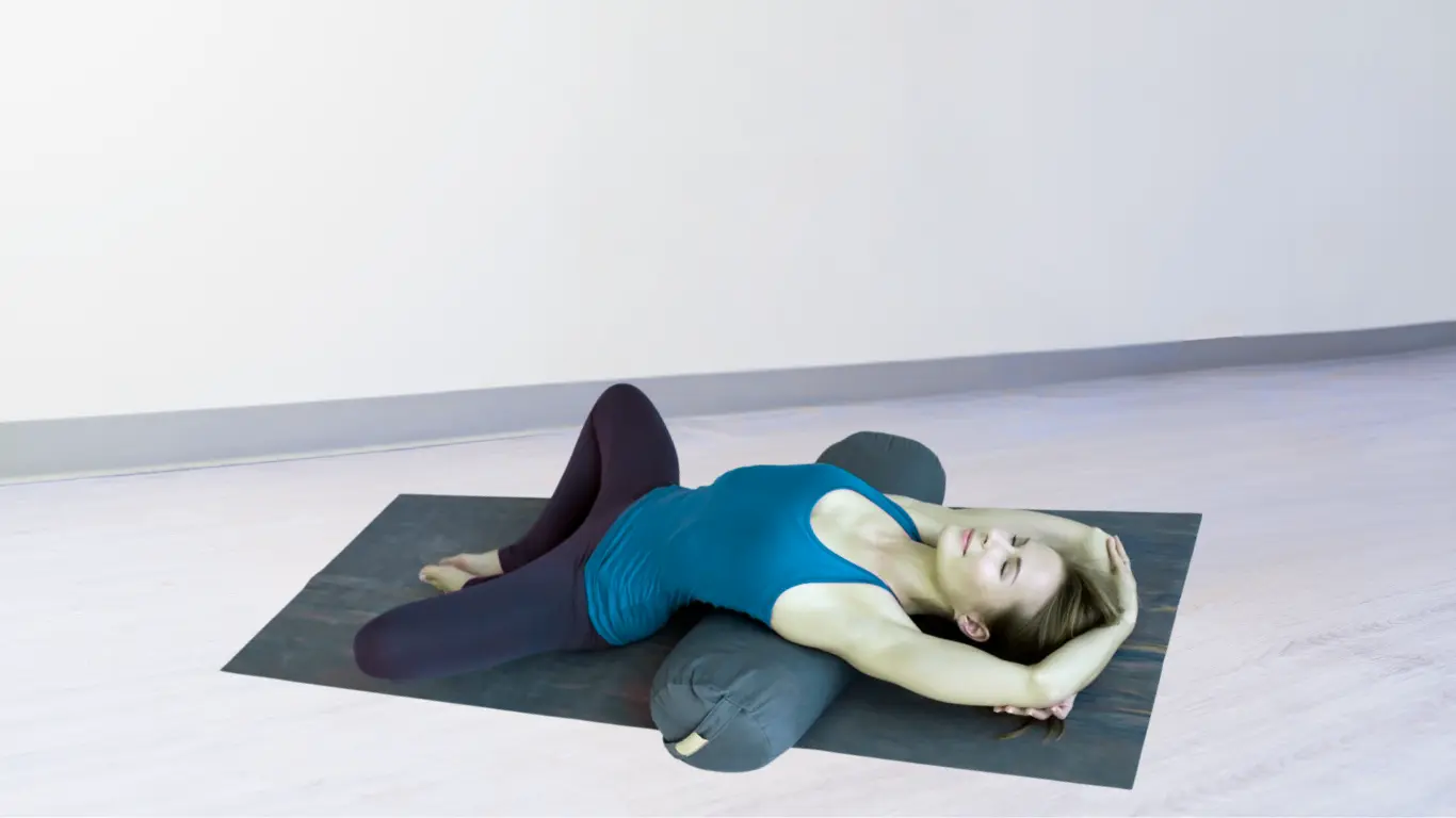 Woman doing supported bridge pose with a yoga bolster under her shoulders and upper back.